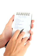 woman's hand holding a notebook with a shopping list close-up