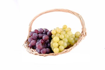 red and green grapes in a straw basket, isolated on white