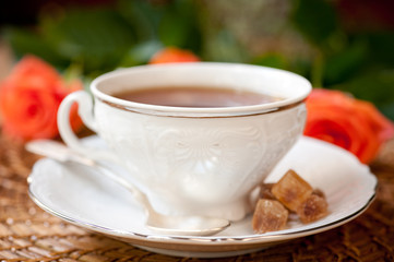 Obraz na płótnie Canvas cup of tea and brown sugar and roses