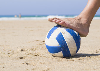 Foot stepping on a ball on the beach (2)