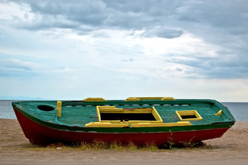 fishing boat on sand with cloudy blue sky and water