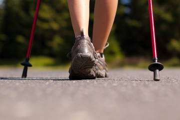Fototapeta na wymiar Closeup of woman's legs with nordic walking poles