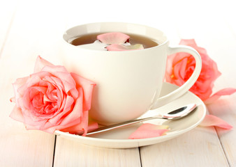 cup of tea with roses on white wooden table