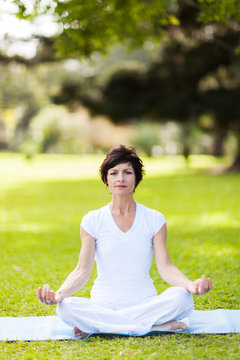 middle aged woman doing yoga meditation outdoors