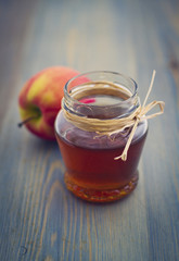 Honey in glass jar and apple on wooden table