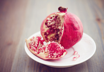 Pomegranate on white plate on wooden table