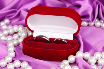 Wedding rings in red box on purple cloth background