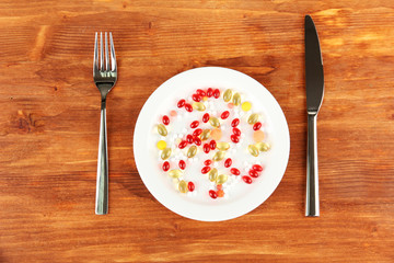 a lot of pills in a plate with knife and fork
