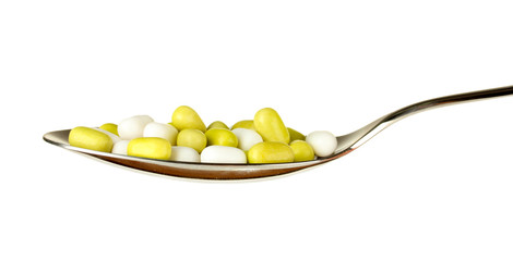 colorful pills on spoon on white background close-up