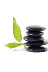 Obraz na płótnie Canvas Balanced black zen pebbles and a young green leaf