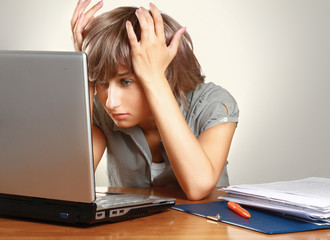 A tired young woman sitting at the desk