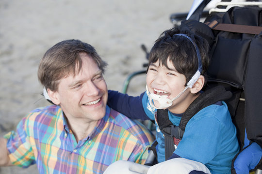 Father enjoying  beach with disabled son