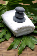 Obraz na płótnie Canvas Stones on towel with green leaf-spa concept