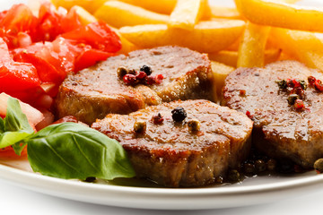 Grilled steaks, French fries and vegetables