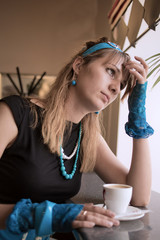 The young woman sits with a cup at a window