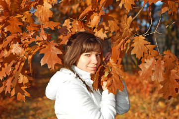 Young woman with autumn orange leaves in forest