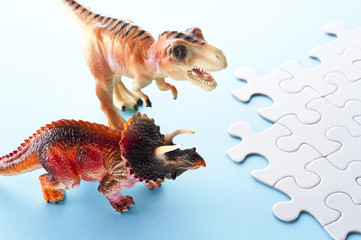 水色の背景に恐竜の玩具とパズル