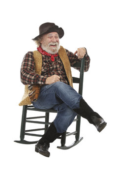 Laughing old cowboy sits in rocking chair