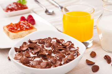 Bowl of chocolate cereal and milk,toast with jam and fruit juice
