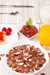 Bowl of chocolate cereal and milk,toast with jam and fruit juice