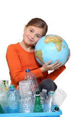 Young girl hugging a globe behind a box of plastic recycling