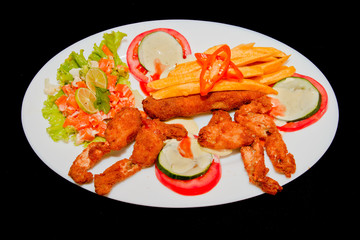 fried frogs legs on a plate isolated in black