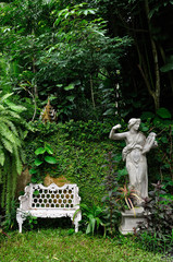 White metal chair and roman sculpture in natural garden