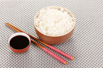 Bowl of rice and chopsticks on grey mat