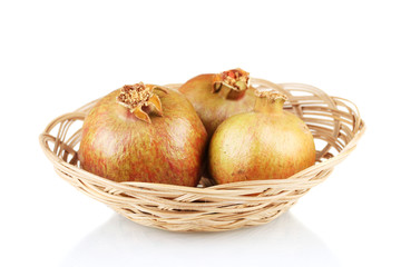 unripe pomegranates in wicker basket isolated on white