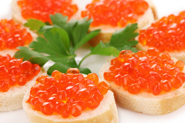 Red caviar on bread on white plate close-up