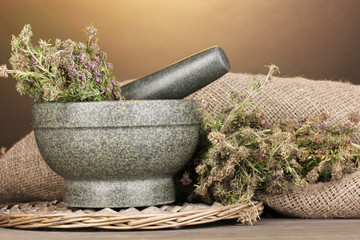 Thyme herb and mortar on wooden table on brown background