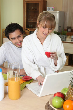 Couple having breakfast in front of laptop