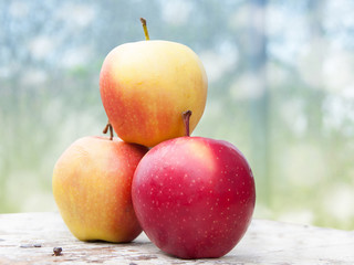 Three red apples on a wooden table