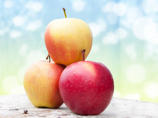 Three red apples on a wooden table