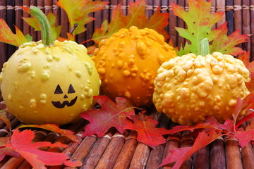 Three gourds and one with a jack-o-lantern face