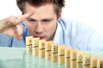 Businessman flicking dominoes