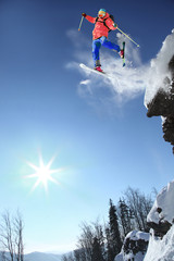 Skier jumping from the cliff in high mountains