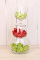 Color candies in glasses on wooden background