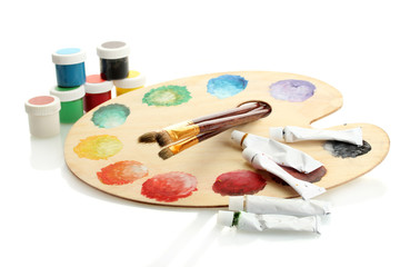 wooden art palette with paint and brushes isolated on white