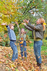 Happy family in autumn forest play with  fallen leaf