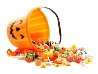 Halloween jack-o-lantern pail with spilling candy over white - Powered by Adobe