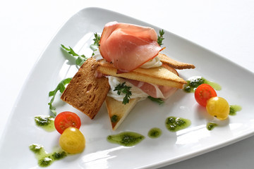 Appetizer with parma ham, melba toast and baby tomatoes
