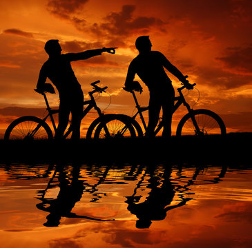 two cyclists silhouette in sunset