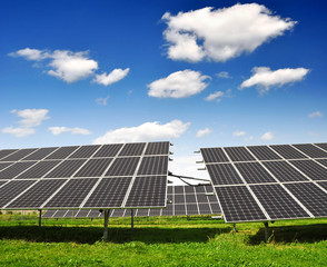 Solar energy panels against blue sky with clouds