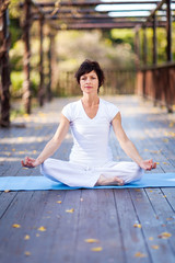 Fototapeta na wymiar middle aged woman doing yoga meditation on deck