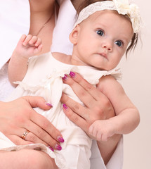 Adorable baby girl in white dress sitting in parent hands