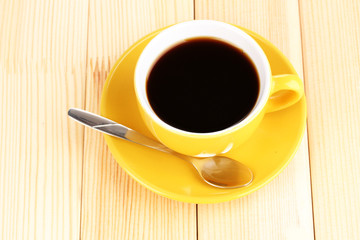 Yellow cup and saucer on wooden background
