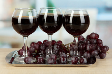 Red wine in glass on salver on room background