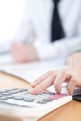 Manager counting on calculator sitting at the table