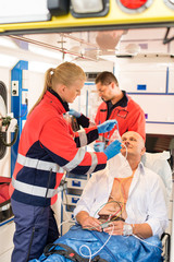 Paramedic putting oxygen mask on patient ambulance